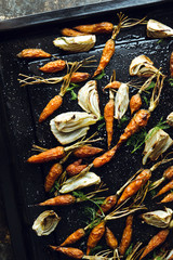 Roasted fennel and baby carrots on tray. Rustic background.