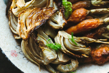 Close up. Roasted fennel and baby carrots on tray. Rustic background.
