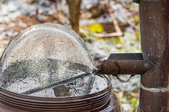 Gekippte Eisplatte in Wasserfass mit Regenrinne