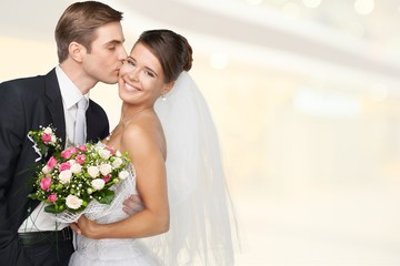 Bride and groom hugging on light background