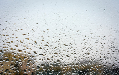 Raindrops on glass, window background view of buildings out of focus.