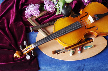 Fototapeta premium Still life with the attributes of art. Violin, palette, brushes, a bouquet of lilac