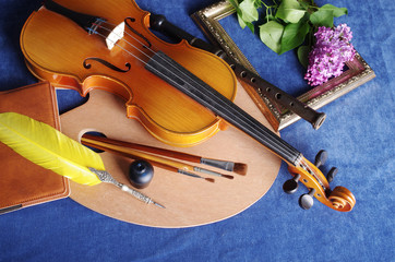 Fototapeta premium Still life with the attributes of art. Violin, palette, brushes, a bouquet of lilac