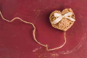 hand made knitted heart with bow on a shabby brown background
