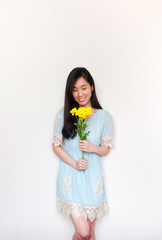 portrait of smilimg asian girl holding bouquet with yelliow flowers with copyspace.