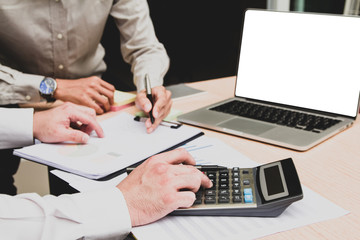 Group businessman hand using calculator Calculating bonus(Or other compensation) to employees to increase productivity.Writing paper on desk.Selective Focus