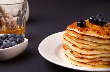 Pancakes with berries and honey on the black background