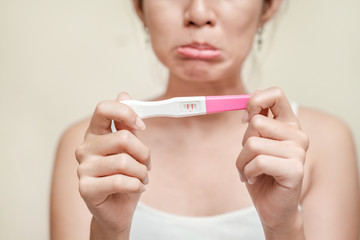 Young asian woman holding pregnancy test showing a positive result, Wellness and healthy concept,...