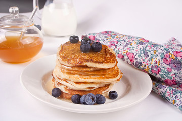 Pancakes with berries and honey on the white background