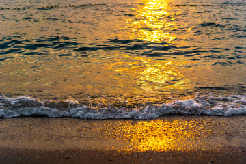 Water waves on beach at sunset time.