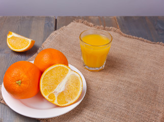 Glass of orange juice and slices of orange fruit on wooden table.