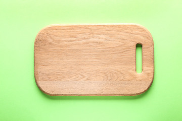Wooden kitchen board on color background