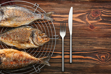 Cooling rack with grilled dorado fish on wooden background