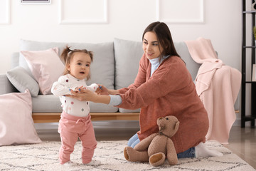 Young woman playing with her cute little daughter at home