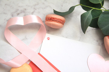 Composition for Valentine's day, pink rose, ribbon, heart, macaroons, eucalyptus, envelope, card, petals