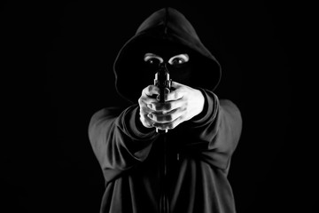 Bandit with gun aiming at viewer on dark background