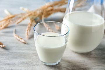 Glass and jug of fresh milk on wooden table