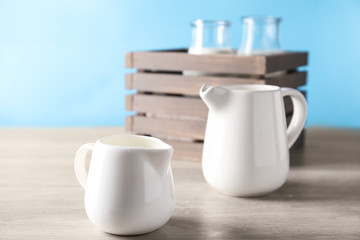 Jugs of fresh milk on wooden table