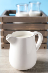 Jug of fresh milk on wooden table