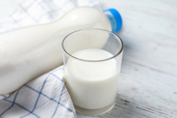 Glass and bottle of fresh milk on wooden table