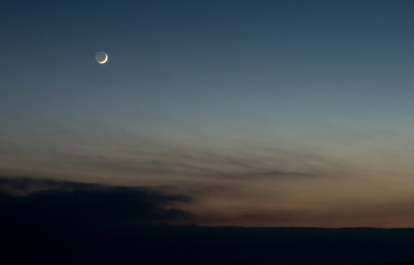 Beautiful sunset sky with crescent moon and dark clouds 