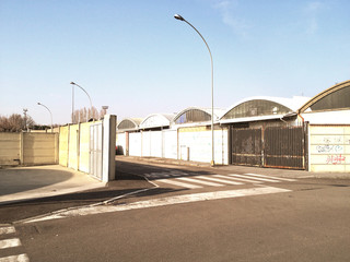 Fototapeta na wymiar Strada con vecchi capannoni industriali nei pressi di Milano, nel 2018.