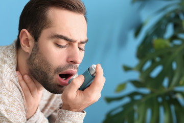 Young man with inhaler having asthma attack at home