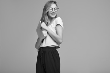 Fototapeta premium Cute teenage girl in white shirt and glasses holding digital tablet