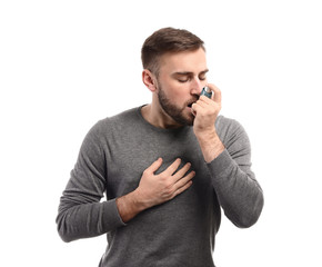Young man with inhaler having asthma attack on white background