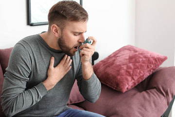 Young man with inhaler having asthma attack at home