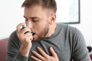 Young man with inhaler having asthma attack at home