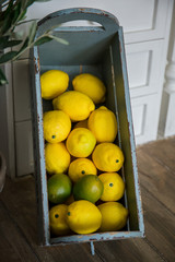 yellow lemons lie in a wooden box in kitchen