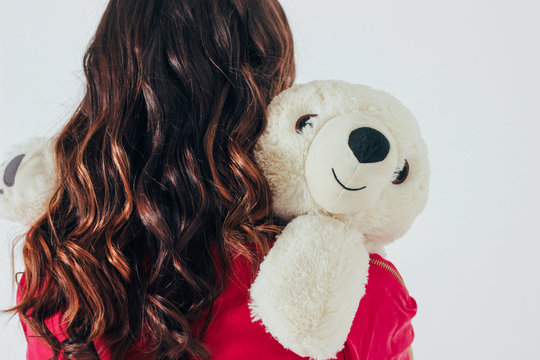 Polar Bear Toy Hugs Young Curly Brunette Woman In Bright Pink Dr