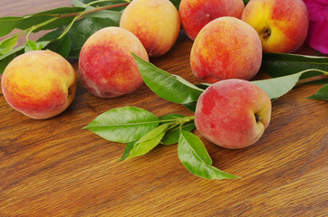 Ripe peaches and leaves on wooden table