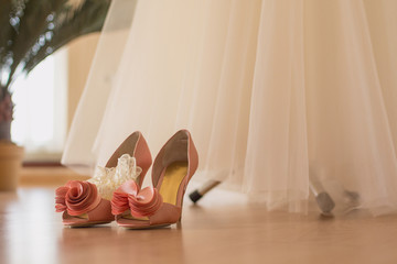 The bride's shoes stand on the floor near the wedding dress