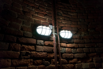 Burning light on the old brick stone wall in the basement