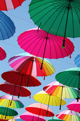 Collection of multi colored umbrellas hanging up.
