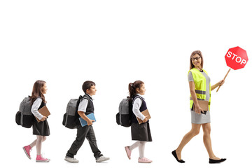 School teacher with a safety vest and stop sign walking with schoolchildren