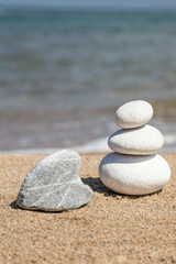 Fototapeta na wymiar heart shaped rock and stack of pebble stones on balance on a beach