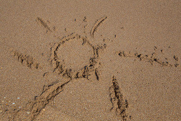 hand drawn sun shape on a sandy beach