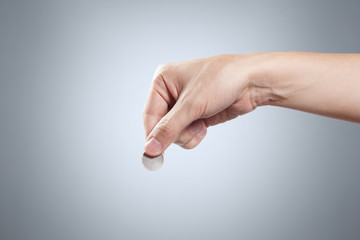 Hand holding a coin on grey background