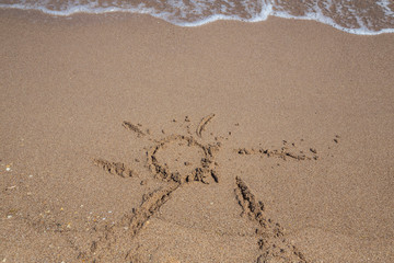 hand drawn sun shape on a sandy beach
