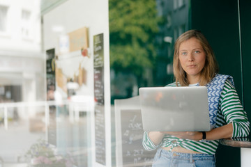 Portrait of young woman with laptop in cafe