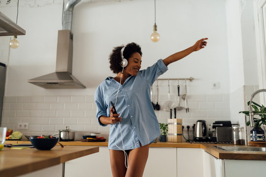 Woman listening to music and dancing in kitchen