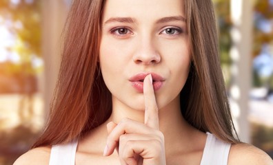 Fototapeta premium Portrait of beautiful young woman with make-up making a hush