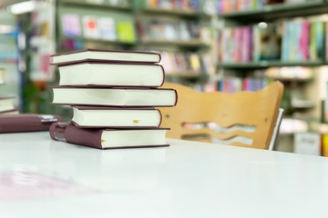 Stack of books put on wooden table near bookshelves in library.Education and business concept for knowledge.