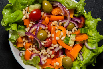 Close up. Italian Greek salad in white bowl. Black background.