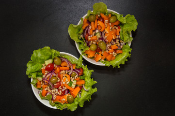 Close up. Vegetarian food. Two bowls of vegetable salad with tofu and pine nuts. Black background. Copy space.