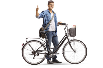 Young smiling man standing with a bicycle and giving thumb up