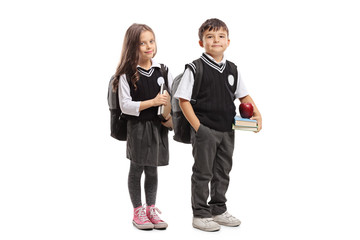 Schoolgirl and schoolboy in a uniform holding books and posing